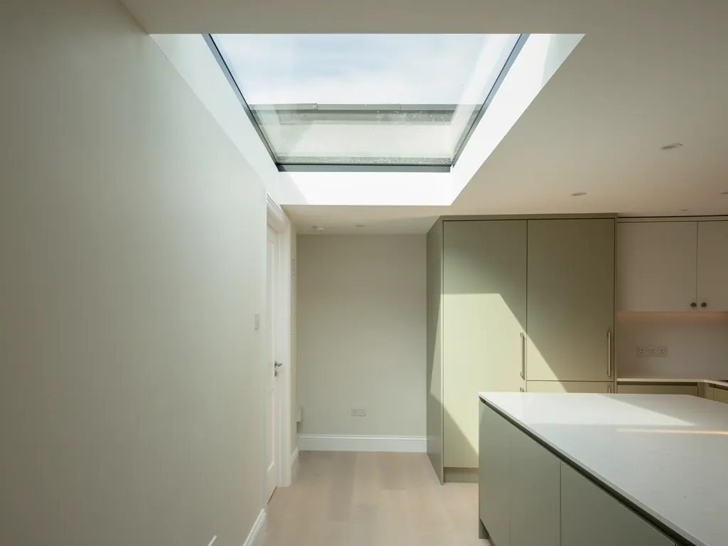 A plastered light well opening up to a flat rooflight above a kitchen